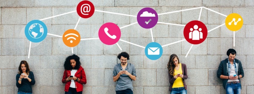 Päť ľudí stojí pri stene a je pohltených svojimi smartfónmi. Nad nimi prepojené ikony – zemeguľa, Wi-Fi, telefón, e-mail, cloud, ľudia a analytika – zachytávajú podstatu digitálnej komunikácie a sietí sociálnych médií, ako je komunikácia cez LinkedIn.