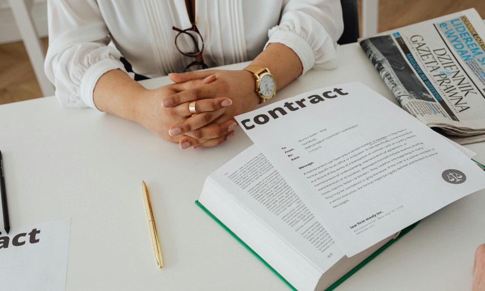 Za stolom ozdobeným zlatým perom, otvorenou knihou a papiermi s nápisom „zmluva“ sedí človek so založenými rukami, čo naznačuje, že sa treba zamerať na výber zamestnancov. Neďaleko sú v tejto profesionálnej kancelárii alebo zasadacom priestore otvorené noviny Gazeta Prawna.